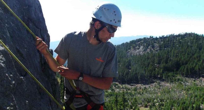 a student looks down while rock climbing in oregon